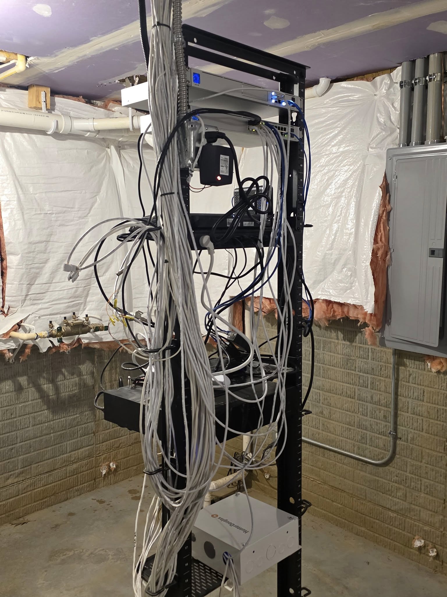 Before: tangled network cabling on open rack in basement